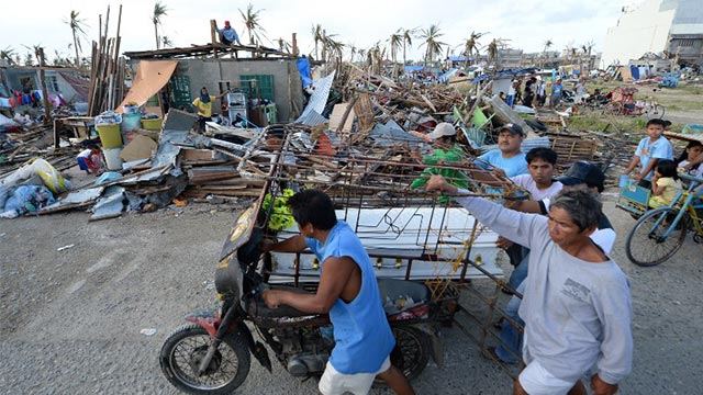 AFTERMATH. Residents push a tricycle converted into a funeral carriage. Photo by AFP/Ted Aljibe