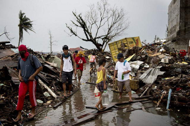 SURVIVING. Survivors of Typhoon Haiyan walk along a road blocked by rubble. Odd Andersen/AFP PHOTO
