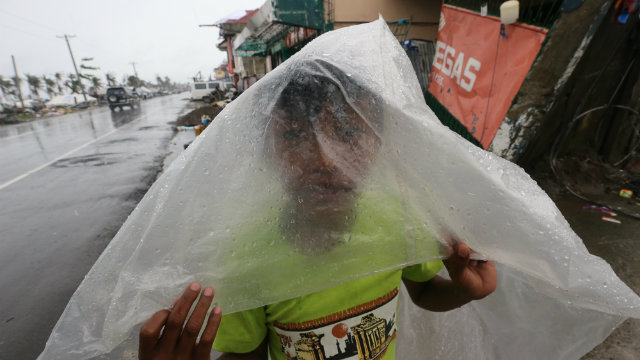 VULNERABLE. An eleven-year old Yolanda survivor uses a plastic sheet to protect himself from a downpour outside their temporary shelter in the typhoon devastated city of Tacloban. Photo by Dennis Sabangan/EPA