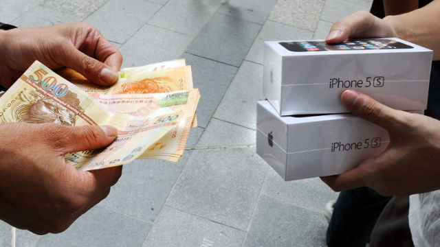 RESOLD. A reseller (L) buys new iPhone 5s handsets from a new iPhone owner (R) outside an Apple store in Hong Kong on September 20, 2013. AFP PHOTO / Laurent FIEVET