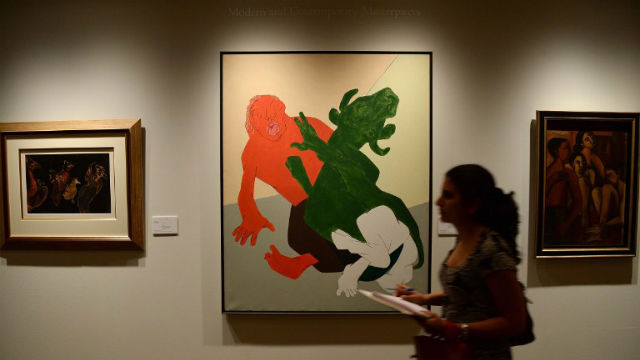 DOUBLE ESTIMATES. A visitor takes notes while walking past Rabindra Nath Tagore's "Untitled" (L), Tyeb Mehta's "Mahisasura" (C) and Ram Kumar's "Untitled (Family)" during a media preview ahead of Christie's first auction in India. AFP Photo
