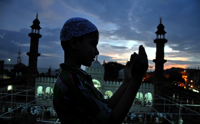 IN PRAYER. A Muslim child, offering prayers, is silhouetted against the evening sky as devotees gather to visualize the moon, ahead of holy month of Ramadan, with the historical Moti Masjid pictured in the background, in Bhopal, India, 09 July 2013. Photo by EPA/Sanjeev Gupta