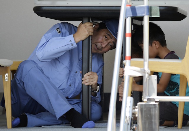 DISASTER DRILL. Japanese Prime Minister Shinzo Abe takes shelter under a table as he experiences an intensity 7 (Shindo scale) earthquake in an earthquake-simulation vehicle at the venue of a major annual earthquake disaster drill in Chiba, east of Tokyo, 01 September 2013. EPA/Franck Robichon