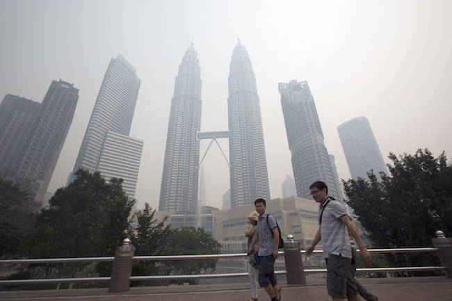 HAZY SKYLINE. Visitors walk through a park near Petronas Towers which is just visible through the haze in Kuala Lumpur, Malaysia 23 June 2013. Photo by EPA/Ahmad Yusni
