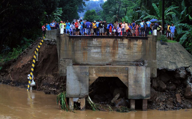 BRIDGE OUT. Residents stand on the edge of a bridge destroyed by flooding brought about by heavy rains in Linamon town, Lanao del norte province, in the southern island of Mindanao on January 14, 2014. Photo by Richel Umel/AFP