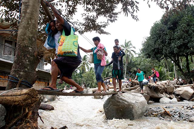 INTENSE FLOODING. Residents walk over a makeshift bridge passing flood waters caused by a landslide after heavy rains in Marayag Village, Lupon town, Davao Oriental. Photo by EPA/Ritchie Tiongco