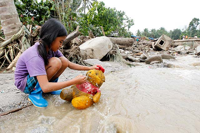 OUT FOR A BATH. Weldel Sametos, 10, scrubs her stuff toy in flood waters after heavy rains in Marayag Village, Lupon, Davao Oriental. Photo by EPA/Ritchie Tiongco