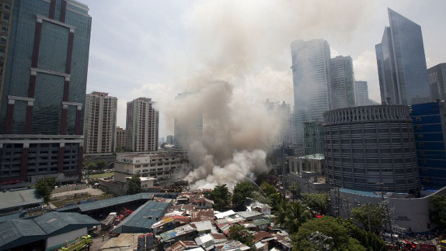 FIRE. Smoke rises after a fire engulfed some houses in Makati City's financial district. Photo from AFP