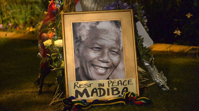 TRIBUTE. A framed image of former South African president Nelson Mandela stands as people pay tributes following his death, in Johannesburg on December 6, 2013. ALEXANDER JOE/AFP PHOTO