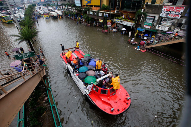 STATE OF CALAMITY. Filipinos get a free ride on a Philippine Red Cross truck through a flooded main road of Epifanio de los Santos Avenue (EDSA), Pasay City, Philippines, 20 August 2013. Photo by EPA/Dennis M. Sabangan 