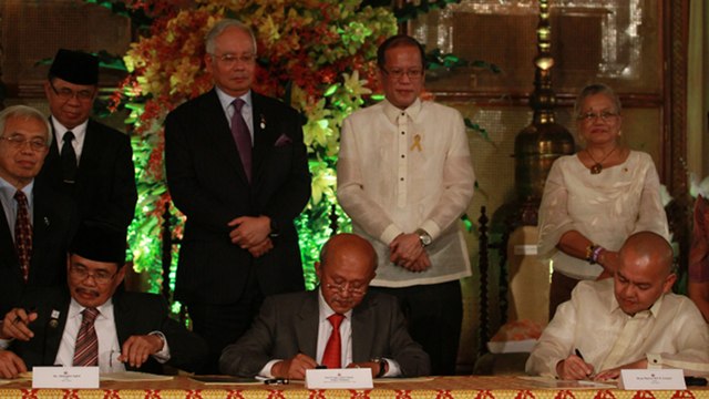 'MOST IMPORTANT DOCUMENT.' MILF Chairman Al Haj Murad Ebrahim (second from left) describes the Framework Agreement on the Bangsamoro as the most important document in this chapter of the MILF's history. He watches the signing of the peace roadmap along with Malaysian Prime Minister Najib Razak and President Benigno Aquino III. MILF Peace Panel Chairman Mohagher Iqbal and Government Peace Panel Chairman Marvic Leonen sign the deal in the presence of Malaysian Facilitator Tengku Dato'Abdul Ghafar. Photo by Malacañang Photo Bureau. 