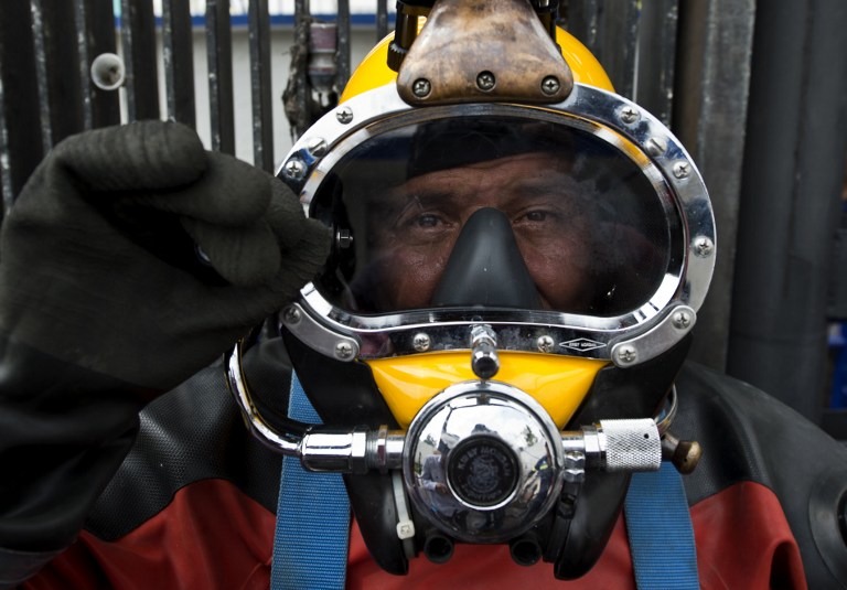 DIVING INTO SEWAGE. Mexican diver Julio Cesar Cu, fully equipped with a KMB hard helmet and a dry suit, prepares to be lowered into the sewage to begin the process of clearing the floodgates of garbage on August 21, 2013, at one of the pumping plants of Mexico City's sewage system. AFP/Ronaldo Schemidt