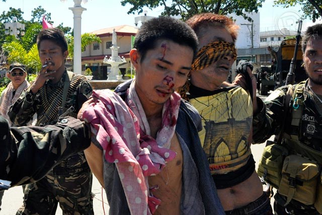 SUSPECT OR HOSTAGE? Men allegedly part of the MNLF group being taken into custody by the military in Sta Catalina, Zamboanga City, September 14, 2013. They insist, however, they are among the civilian hostages. Photo by LeAnne Jazul/Rappler