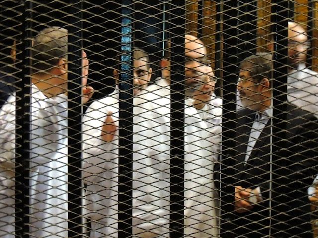 BEHIND BARS. Ousted Egyptian president Mohamed Morsi (R) stands behind bars with other unidentified Muslim Brotherhood defendants during first trial session, in Cairo, Egypt, 04 November 2013. EPA/Egyptian Interior Ministry handout