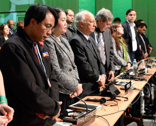 A MOMENT OF SILENCE. Naderev Sano and other delegates pay standing tribute to victims of Typhoon Haiyan during the UN Climate Change Conference COP 19 on November 11, 2013  AFP PHOTO/JANEK SKARZYNSKI