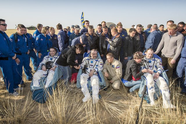 BACK HOME. (L-R) ISS Expedition 36 astronaut Chris Cassidy of NASA, and cosmonauts Pavel Vinogradov and Alexander Misurkin, sit in chairs outside the Soyuz TMA-08M capsule just minutes after they landed in a remote area near the town of Zhezkazgan, Kazakhstan, on Wednesday, Sept. 11, 2013. NASA/Bill Ingalls