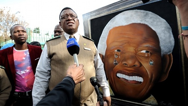 STILL CRITICAL. A member of the Correctional Services speaks as he unveils a painting portraying Nelson Mandela and drawn by a former prisoner on July 11, 2013 outside the MediClinic Heart Hospital in Pretoria. AFP/Stephane de Sakutin 