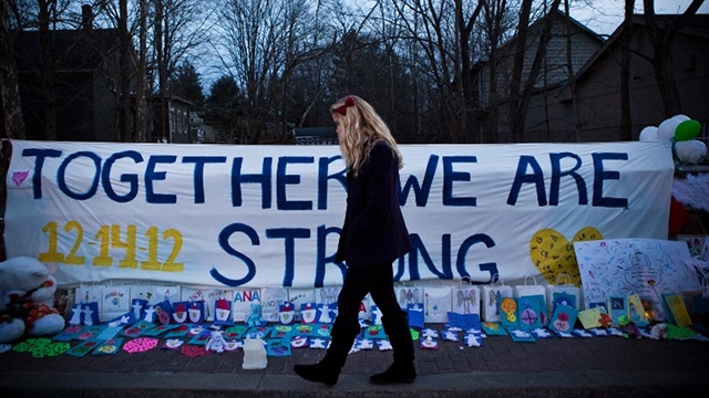 LONG RECOVERY. A woman walks past a sign that at a memorial for those killed in the school shooting at Sandy Hook Elementary School on December 24, 2012 in Newtown, Connecticut. Donations and letters are pouring in from across the country as the town tries to recover from the massacre. Survivors prepare to go back to school on January 3. Andrew Burton/Getty Images/AFP