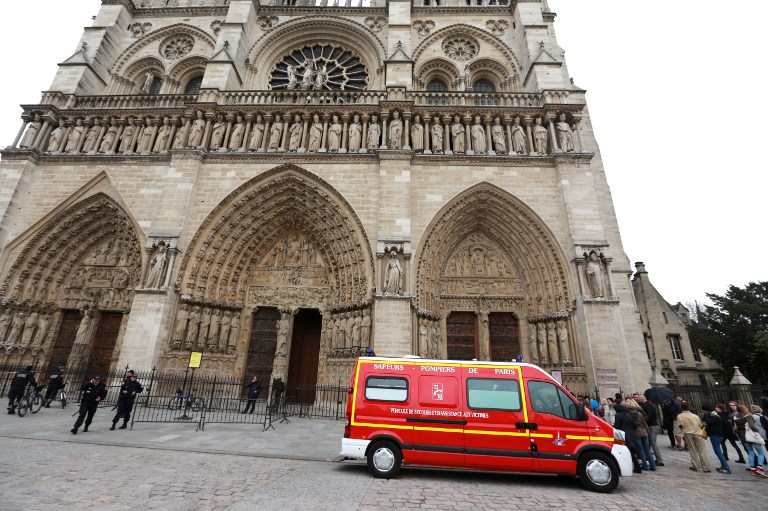 DEATH AT THE NOTRE DAME. French policemen stand at attention near a vehicle of French firefighters outside Paris' Notre Dame Cathedral, on May 21, 2013, following the evacuation of the cathedral after a man shot himself dead in front of the altar. AFP PHOTO / PIERRE VERDY