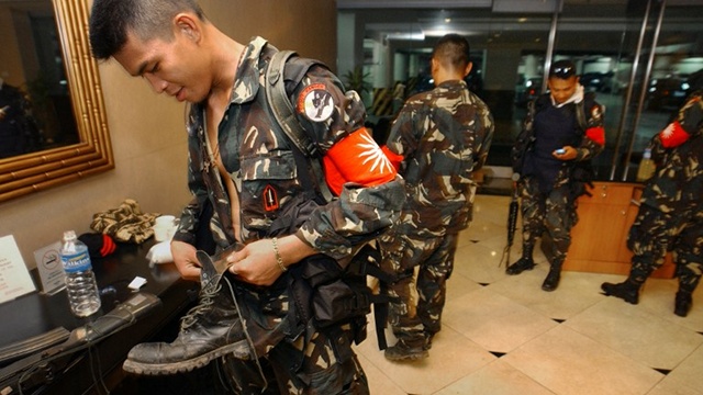 MAGDALO SOLDIERS. An unidentified rebel soldier checks his boots while his comrades secure the basement of the luxury Oakwood hotel in Makati on July 27, 2003, during their failed military mutiny. File photo from AFP