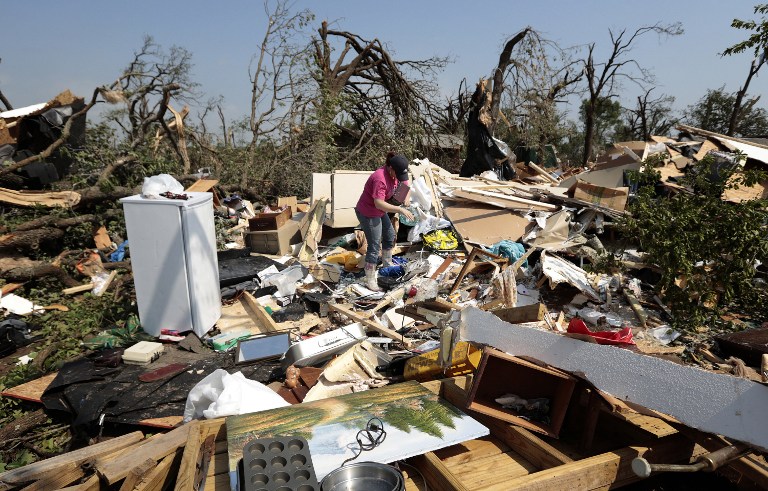 LIFE IN RUINS. Kasey Clark sorts through the debris of her grandmother-in-law Thelma Cox's mobile home after it was destroyed by a tornado May 20, 2013 near Shawnee, Oklahoma. Brett Deering/Getty Images/AFP