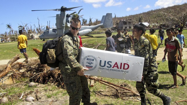 FROM THE AMERICAN PEOPLE. U.S. Marine Capt. Joseph White (L) and Philippine army Pfc. Vic D. Victorlano (R) carry USAID relief supplies from an MV-22 Osprey in Basey, Samar, Philippines, Nov. 18, 2013. Photo by the US Department of Defense/US Marine Corps Capt. Caleb Eames