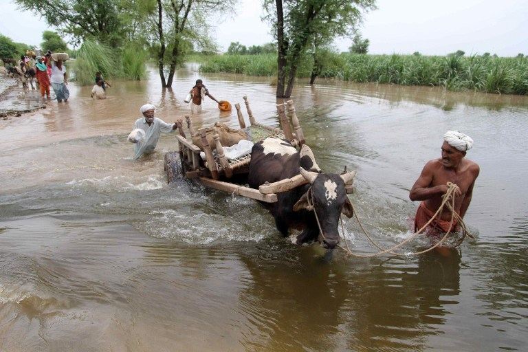 MONSOON FLOODS. Pakistani flood affected villagers wade through floodwaters as they evacuate their homes at Sadat Wala near Multan on August 16, 2013. Photo by AFP/ S S Mirza