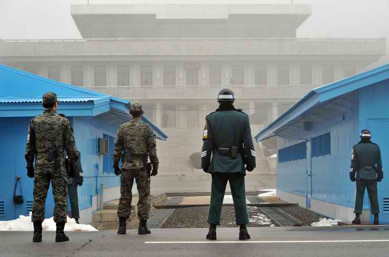 TRUCE IN DANGER? South Korean soldiers stand guard in fog as a North Korean soldier (C far) is seen at the truce village of Panmunjom in the demilitarized zone dividing North and South Korea on February 27, 2013. AFP PHOTO / JUNG YEON-JE