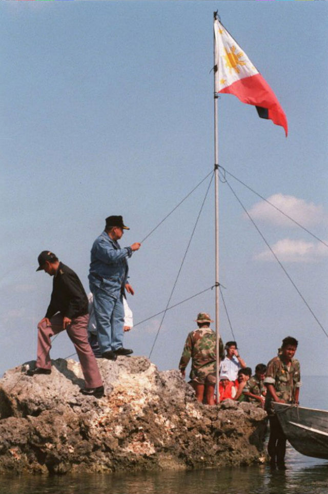 'ROCK, NOT ISLAND.' A file photo dated May 17, 1997 shows the Philippine flag flying as a team from the Philippine Navy and 3 congressmen from the House Committee on Defense climb the tiny rock of Manila-claimed Scarborough Shoal. File photo by AFP
