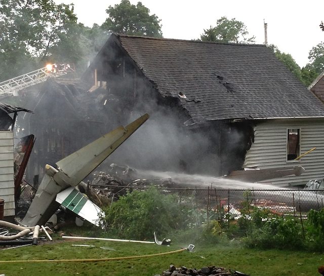 CRASH. The tail of a small aircraft sits behind a burned home following a crash in East Haven, Connecticut, USA 09 August 2013. Photo by EPA/Marek Pienkos