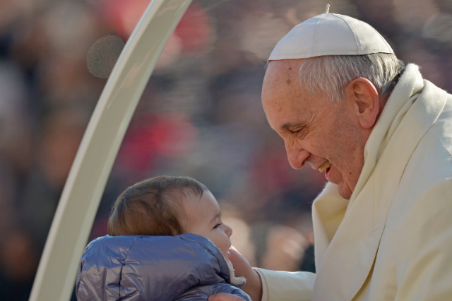 BUAH PERNIKAHAN. Paus Fransiskus menggendong seorang bayi, buah dari pernikahan. Foto oleh AFP