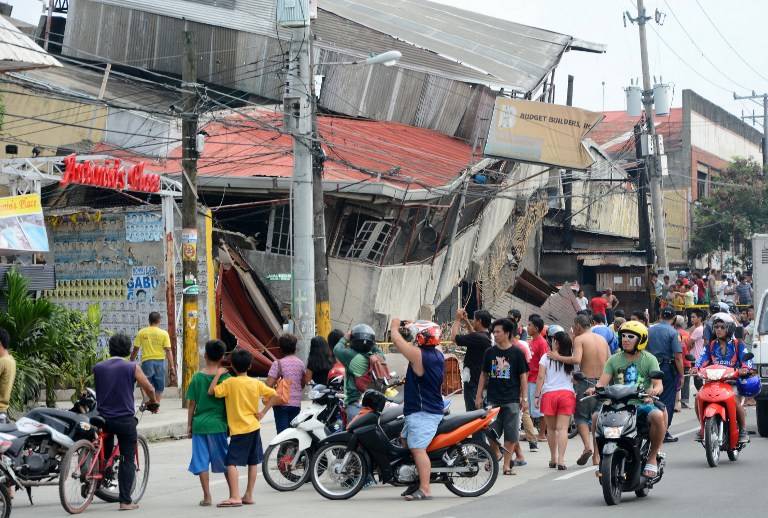 COLLAPSED. People gather on the street next to damaged buildings in Cebu City, Philippines after a major 7.1 magnitude earthquake struck the region on October 15, 2013. AFP