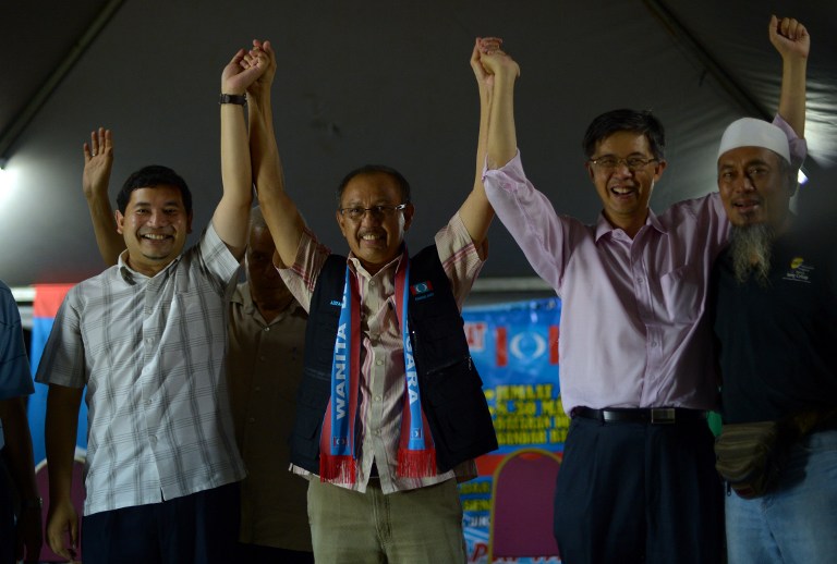 This picture taken on February 15, 2013 shows Rafizi Ramli (L), the strategist for the polical party of opposition leader Anwar Ibrahim, joining hands with other political leaders at a late night corner meeting in Kuala Lumpur. AFP PHOTO / SAEED KHAN