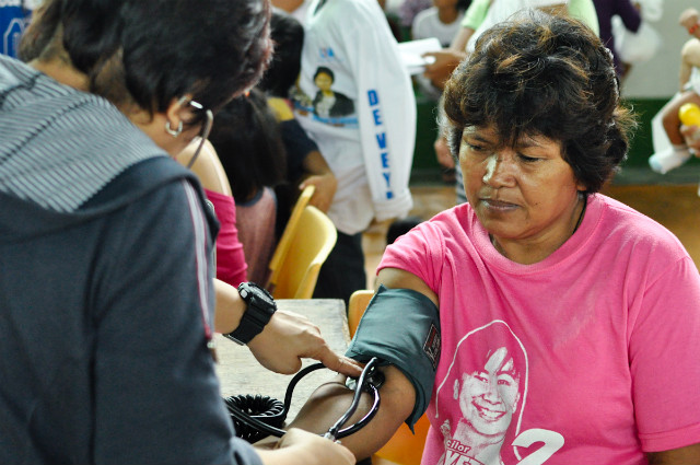 SERVING EVACUEES. A woman takes the blood pressure of an evacuee in Bangkal Sports Complex, Makati City. Photo by Jay Ganzon.