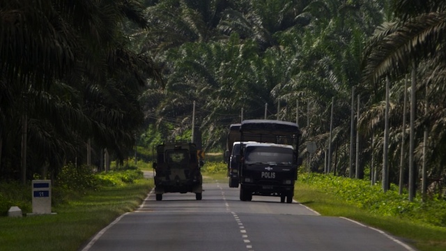 DEADLY STANDOFF. Malaysian police (R) and an army truck drive past each other in Lahad Datu on the Malaysian island of Borneo on March 3, 2013. AFP PHOTO / MOHD RASFAN