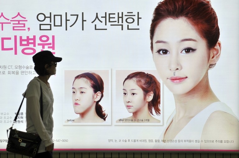 SURGERY-OBSESSED NATION. This picture taken on May 22, 2013 shows a South Korean woman walking past a street billboard advertising double-jaw surgery at a subway station in Seoul. Photo by AFP / Jung Yeon-Je