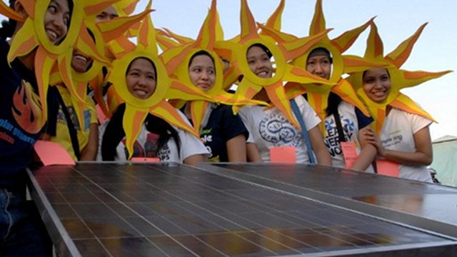 SUNNY. Advocates wear sunburst headdresses and pose next to a solar panel. File photo by AFP