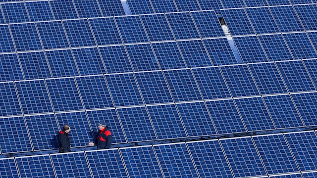 SOLAR POWER. Two men stand in the new solar power plant of operating company Norddeutsche Energiegemeinschaft in Buetzow, Germany, 15 March 2013. Photo by EPA/Jens Buettner