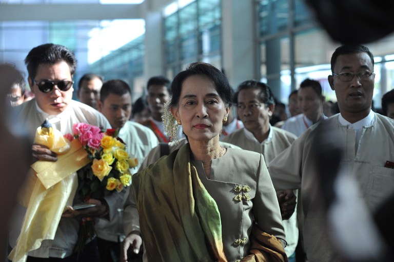 Myanmar opposition leader Aung San Suu Kyi (C) arrives at Yangon International Airport before departing on an overseas trip to Hawaii and South Korea on January 24, 2013. AFP PHOTO / Ye Aung THU