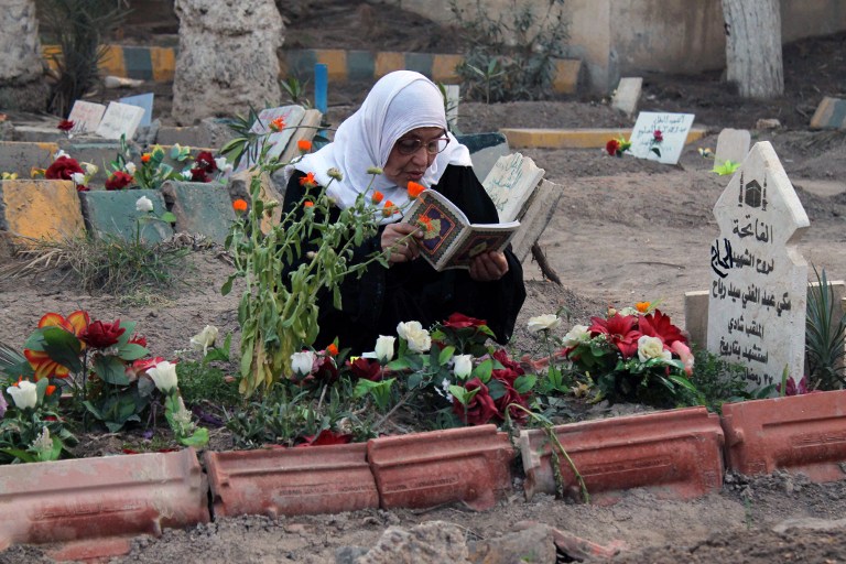FROM PARK TO CEMETERY. A woman reads the Koran, the Muslim holy book, next to the grave of one relative buried in a public park on March 11, 2013 in Syria's eastern city of Deir Ezzor. Men, women and children, and sometimes fighters barely out of adolescence -- every day Al-Mashtal park in the city becomes the final resting place for new victims of the conflict that has torn Syria apart for over two years. AFP PHOTO / JOSE RODRIGUEZ