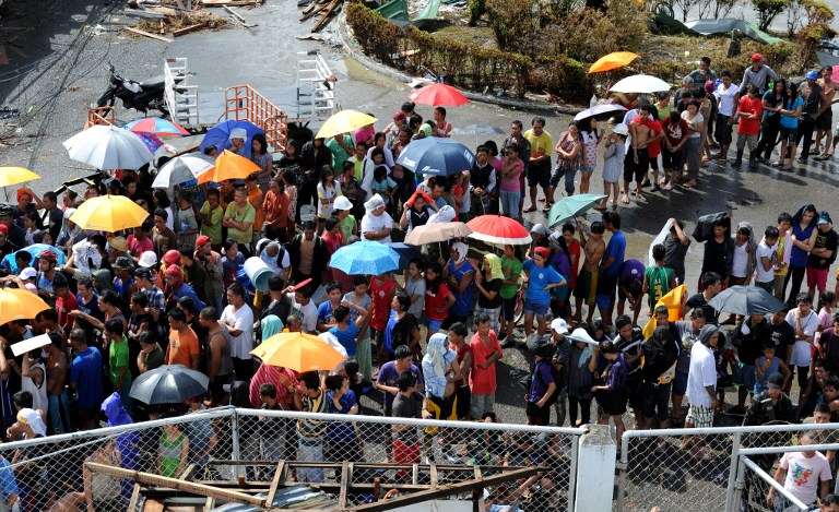 WAITING FOR AID. Typhoon survivors queue up to receive relief goods being distributed at the Tacloban airport in Tacloban City, Leyte, on November 10, 2013. AFP/ Ted Aljibe