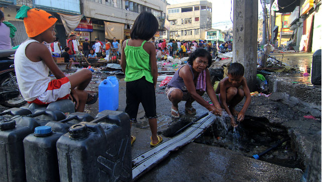 HUNGRY, THIRSTY. In Tacloban City, a resident uses a busted pipe for water. Photo by Vincent Go