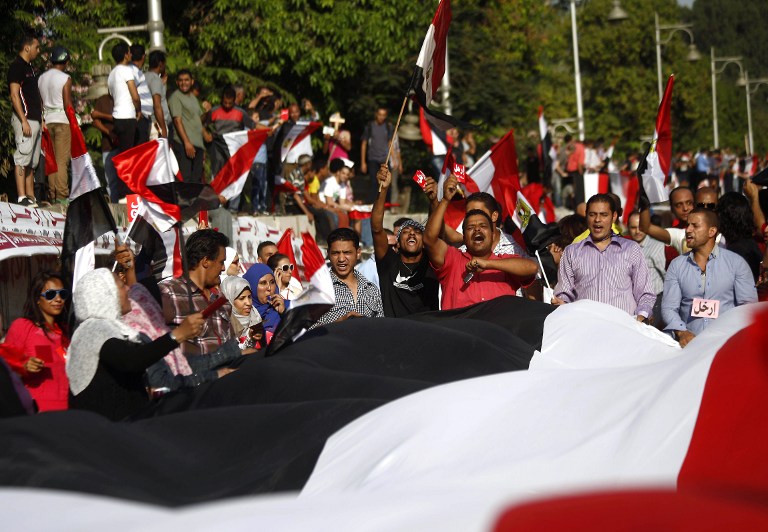 ANGER IN THE STREETS. Opponents of Egypt's Islamist President Mohamed Morsi shout slogans while holding a giant Egyptian flag during a protest calling for his ouster outside the presidential palace in Cairo on June 30, 2013. AFP/Mahmud Khaled