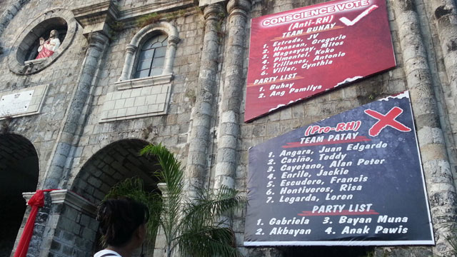 DEFYING COMELEC. The Bacolod Diocese cuts its oversized poster into half. Photo by Charlie Saceda