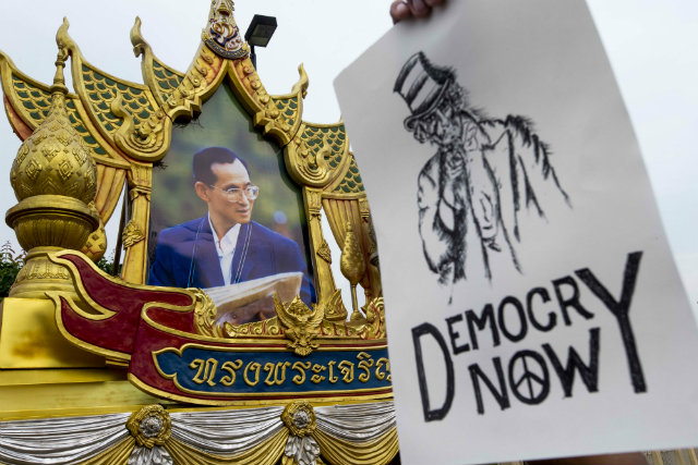 PROTEST. A Thai protester holds a placard as he marches past a portrait of King Bhumibol Adulyadej during a rally against the military junta at Victory Monument in Bangkok, Thailand on May 26, 2014. Thai army chief General Prayuth Chan-ocha received a royal endorsement as junta head but gave no indication of when civilian rule would be restored. Photo by Diego Azubel/EPA