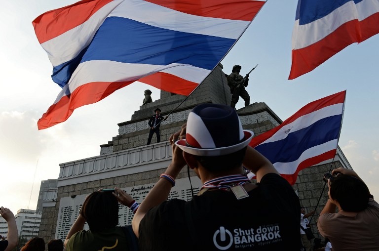 'BANGKOK SHUTDOWN.' Thai anti-government protesters take pictures as a man waves a giant national flag from the Victory Monument, one of the sites occupied by protesters in Bangkok on January 13, 2014. Christophe Archambault/AFP