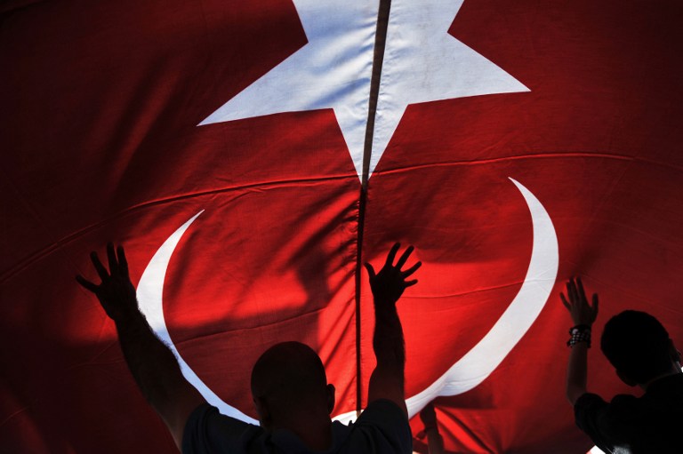 UNDER THE FLAG. Protesters chant slogans under a giant Turkish flag during a demonstration on June 9, 2013 on Gundogdu square in Izmir. Photo by Ozan Kose/AFP