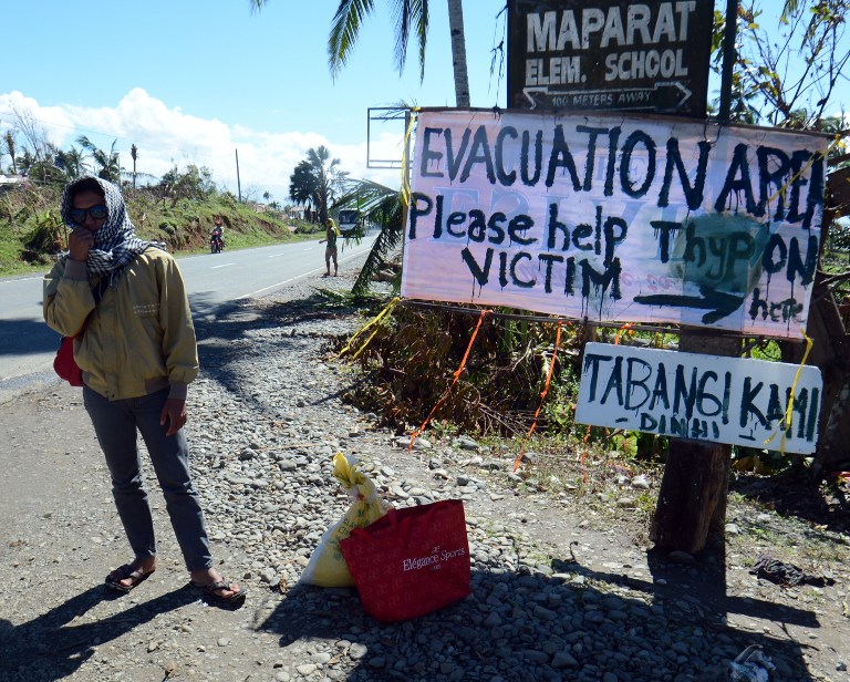 "TABANGI KAMI DINHI." A resident stands next to a sign near a school serving as an evacuation center for victims of Typhoon Pablo (Bopha) in the town of Maparat in Compostela Valley province on December 8, 2012. AFP PHOTO / TED ALJIBE