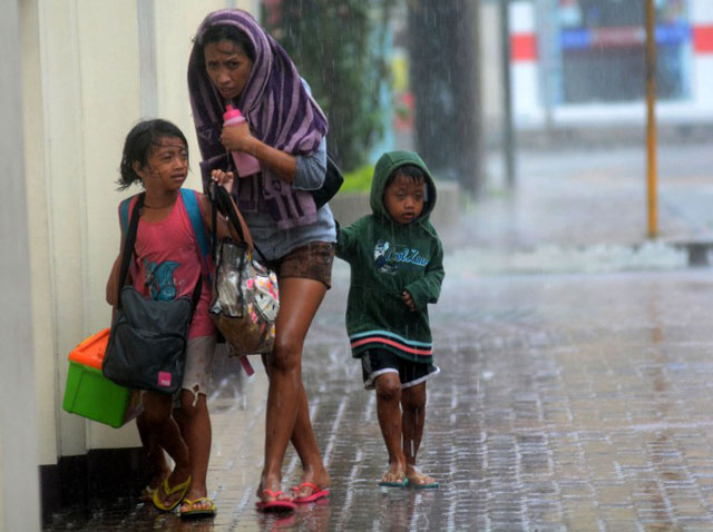 MOVING OUT. With belongings in tow, a family braves the rains brought by Yolanda (Haiyan) in Cebu City. AFP file photo