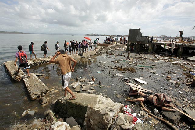 DEAD BODIES EVERYWHERE. Villagers walk past a dead body laying on damaged breakwater in Tacloban city. Photo by EPA/Francis Malasig